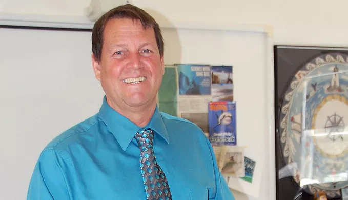 Coach Kenneth Merrill posing for a picture in a classroom.