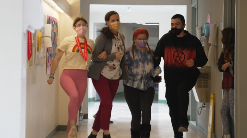 Several students from Riverview School link arms and skip down the hall of a building with a staff member.