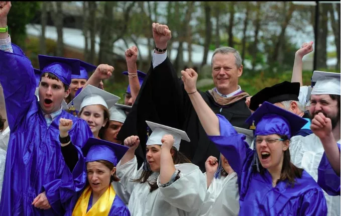 A crowd of students wearing blue and white graduation gowns and caps, with a few staff wearing black graduation gowns.
