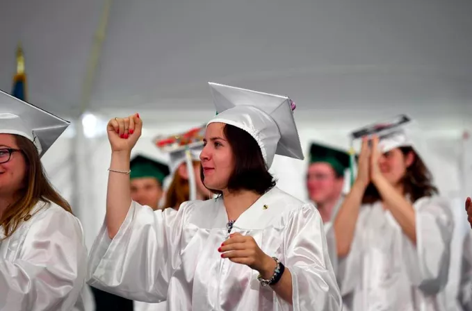 Several students wearing white and green graduation gowns and caps.