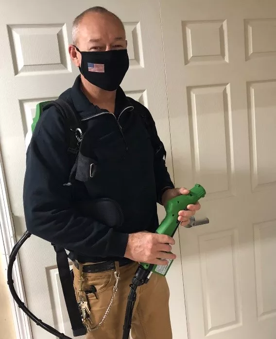 A man, Rich Garnett, wearing a face mask and a portable fogger for sanitation purposes.