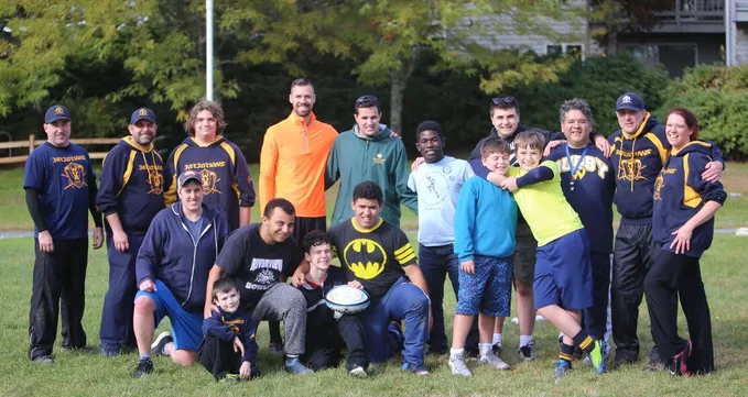 The rugby club, The Barbarians, posing with several students from Riverview School.